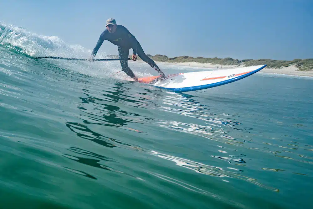 Un homme surfe sur une vague en équilibre sur sa planche de surf