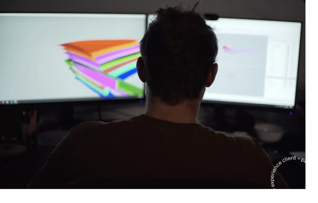 Un homme assis devant deux écrans d'ordinateur